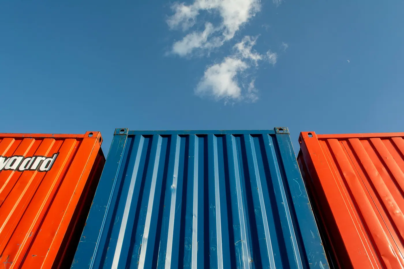 Orange and blue shipping containers stacked against a clear sky