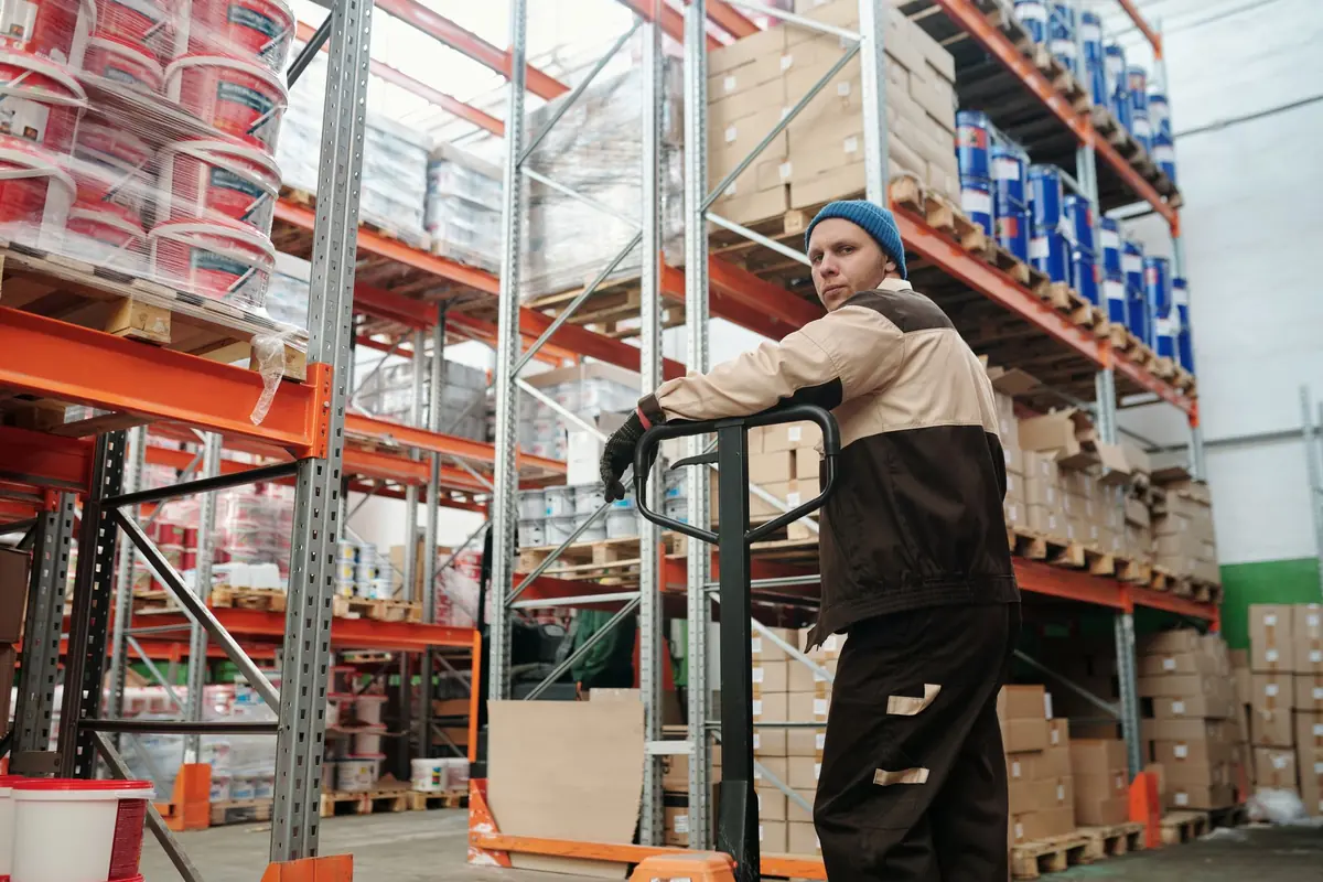Warehouse operator moving stacked boxes with a pallet jack